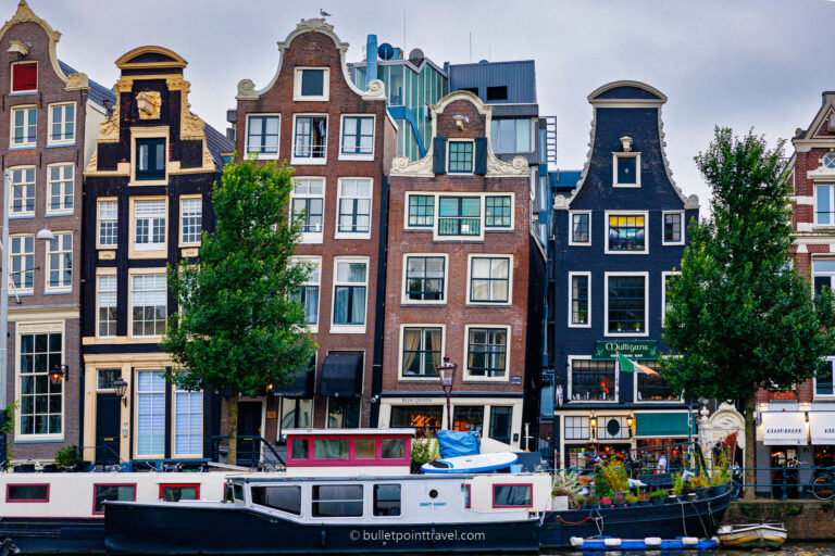 traditional Amsterdam buildings with a house boat in the forefront